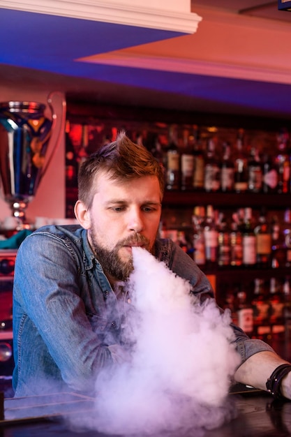 Bezpłatne zdjęcie vape. vaping człowiek w chmurze pary. zdjęcie zostało zrobione w vape barze. sklep z e-papierosami