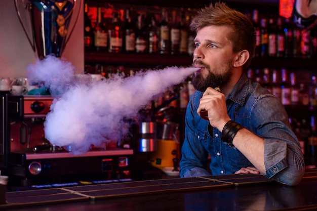 Bezpłatne zdjęcie vape. vaping człowiek w chmurze pary. zdjęcie zostało zrobione w vape barze. sklep z e-papierosami