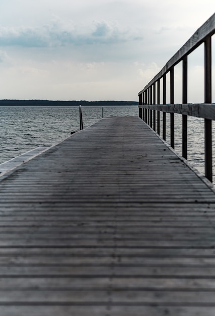 Vertical strzał drewniany molo przy cpast piękny widzii pod chmurnym niebem