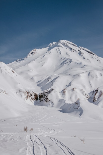 Vertical strzał piękna śnieżna góra strzelająca od stromego wzgórza z niebieskim niebem w tle