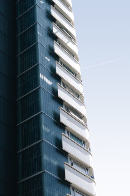 Vertical szklany budynek z białymi balkonami pod niebieskim niebem