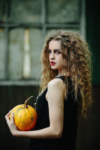 Vintage kobieta jako wiedźma, pozująca na tle opuszczonego miejsca w przeddzień Halloween