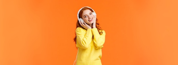 W pasie portret słodkie nastoletnie rude dziewczyny w białych słuchawkach przechylić głowę słuchać muzyki dotykać słuchawki