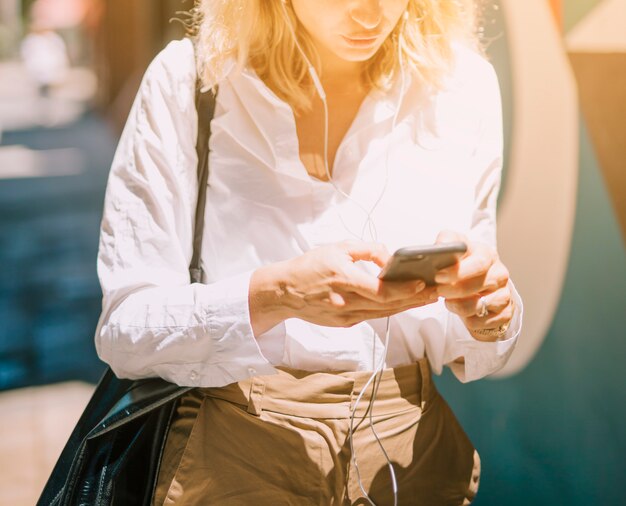 W połowie sekcja blondynki młoda kobieta używa telefon komórkowego przy outdoors