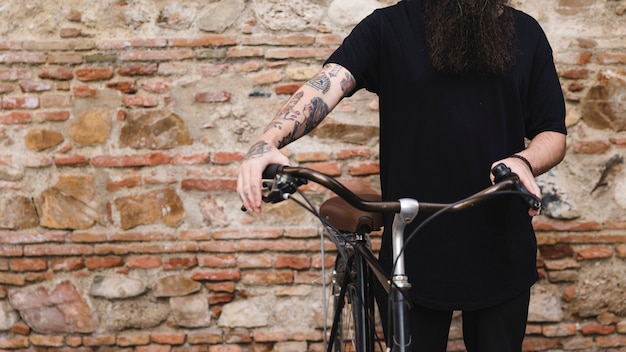 Bezpłatne zdjęcie w połowie sekcja mężczyzna pozycja z bicyklem przeciw ścianie