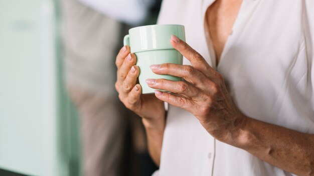 W połowie sekcja starsza kobieta trzyma filiżankę kawy