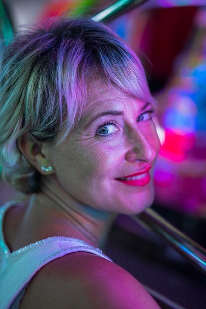 W średnim wieku uśmiechnięta kobieta zastanawia się przy jarzyć się lampy