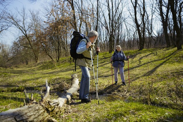 W wieku para rodziny mężczyzny i kobiety w strój turystyczny spaceru na zielonym trawniku