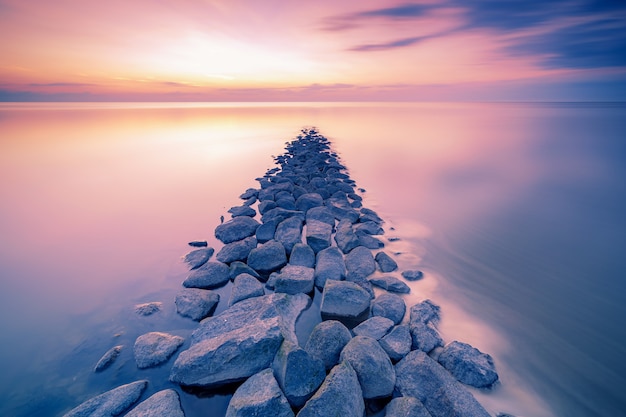 Bezpłatne zdjęcie waddenzee lub morze waddowe podczas zachodu słońca widzianego z molo promem kamieni w holenderskiej prowincji fryzja