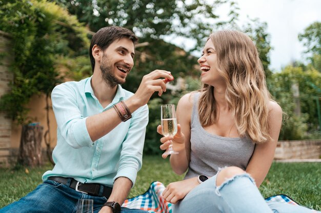 Wakacje, ludzie, romans, mężczyzna i kobieta karmią się truskawkami, pijąc musujące wino i ciesząc się razem w domu