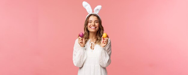 Wakacje wiosna i przyjęcie koncepcja Portret uroczej wesołej blond dziewczyny w uszach królika trzymającej kolorowe jajka świętujące Wielkanoc z rodziną, ciesząc się spędzaniem tradycyjnego dnia z bliskimi ludźmi