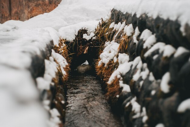 Wąska ścieżka między stosami siana pokrytego śniegiem