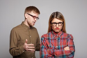 Bezpłatne zdjęcie wasza europejska para kłócąca się: brodaty facet w owalnych okularach próbuje przekonać swoją upartą dziewczynę, która krzyżuje ramiona i robi niezadowolony grymas, wyrażając sprzeciw