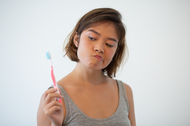 Wątpliwa ładna kobieta patrzeje toothbrush