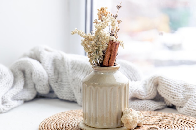 Bezpłatne zdjęcie wazon z suszonymi kwiatami i laskami cynamonu na niewyraźnym tle