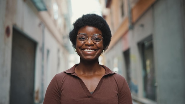 Wesoła Afrykańska kobieta w okularach wygląda na szczęśliwą na zewnątrz Carefr