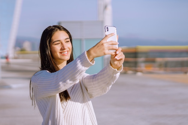 Wesoła brunetka z szerokim uśmiechem robi selfie