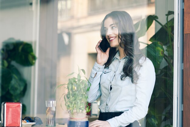 Wesoła dziewczyna rozmawia przez telefon w restauracji