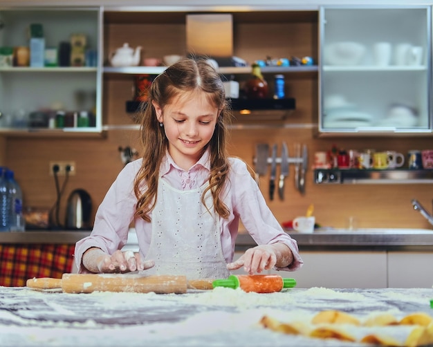Wesoła mała dziewczynka gotowania ciasta w kuchni.