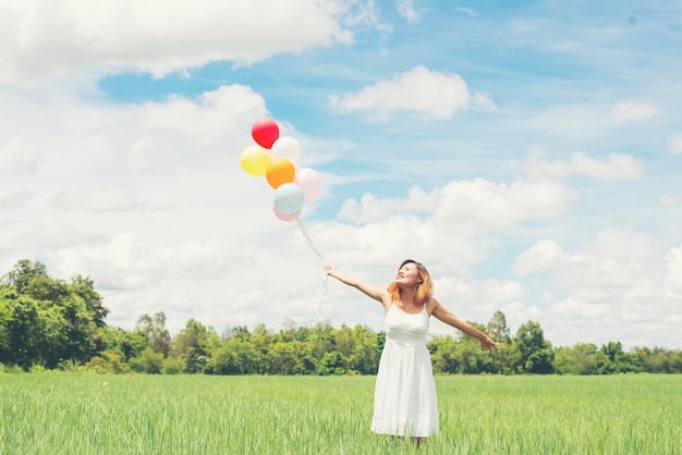 Wesoła młoda kobieta bawi się z balonów w słoneczny dzień