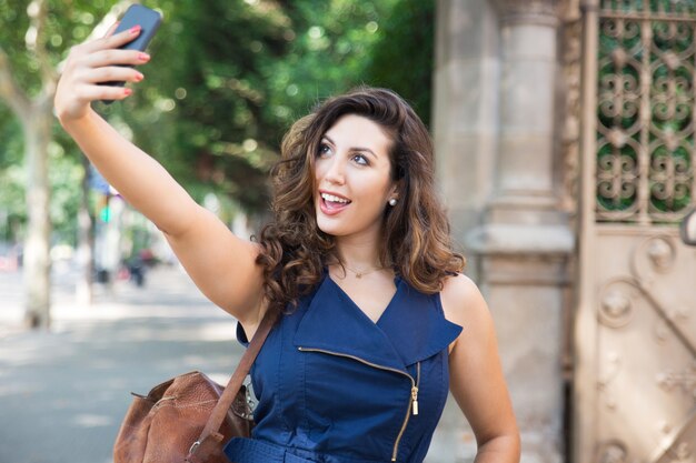 Wesoła młoda kobieta biorąc selfie na zewnątrz pomieszczeń