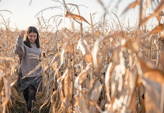 Wesoła młoda kobieta na polu kukurydzy jesienią