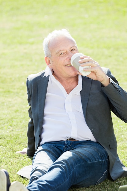 Wesoła picia kawy Pracownik siedzący na trawie