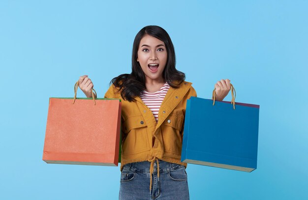 Wesoła szczęśliwa nastoletnia azjatycka kobieta ciesząca się zakupami, niesie torby na zakupy