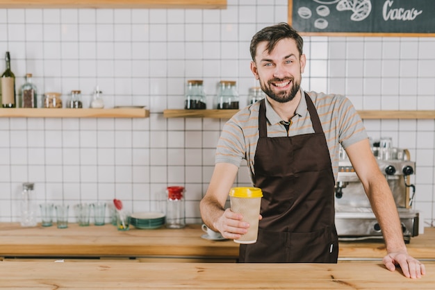 Bezpłatne zdjęcie wesoły barista z kubkiem