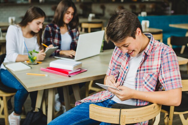 Wesoły chłopiec z tabletkami i kolegami z klasy