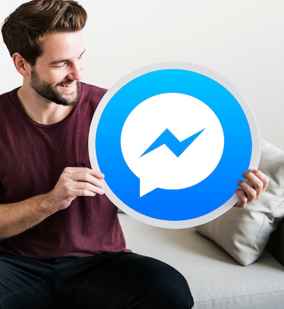 Bezpłatne zdjęcie wesoły człowiek posiadający ikonę facebook messenger