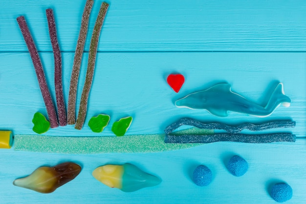 Wesoły obrazek smacznych galaretek w kształcie ryby i fal na drewnianym turkusowym stole