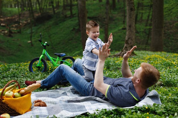 Wesoły tata i syn zabawy grając na pled w zielonym parku