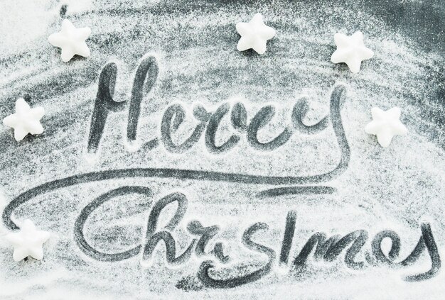 Wesołych Świąt Bożego Narodzenia napis między ozdobny śnieg i gwiazdy