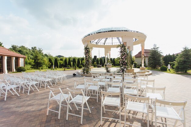 Widok białych krzeseł dla gości i zdobione uroczyste brama na świeżym powietrzu w słoneczny dzień