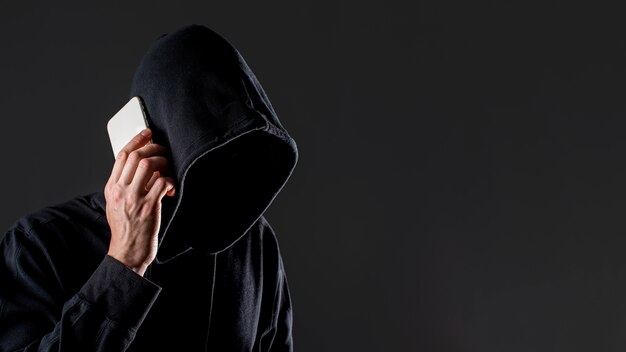 Widok boczny mężczyzny-hakera rozmawiającego na smartfonie z przestrzenią do kopiowania