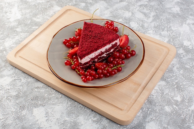 Widok do połowy góry kawałek czerwonego ciasta kawałek ciasta owocowego wewnątrz płyty ze świeżymi żurawinami i truskawkami na drewnianym biurku ciasto słodkie herbatniki