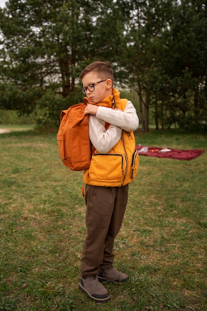Bezpłatne zdjęcie widok małego chłopca badającego naturę z plecakiem