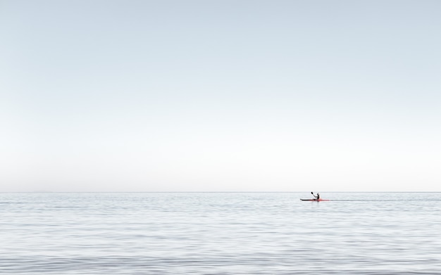 Widok mężczyzny pływającego kajakiem po bardzo spokojnej wodzie na morzu