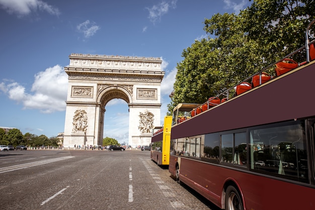 Widok na łuk triumfalny i autobusy turystyczne w słoneczny dzień w paryżu