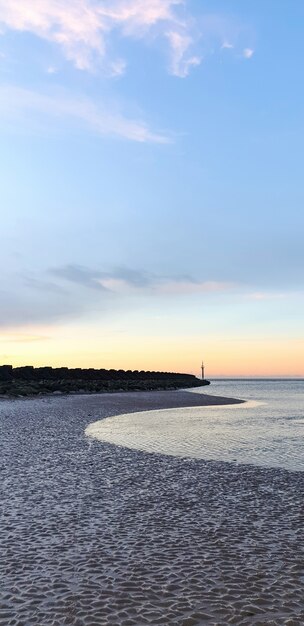 Widok na plażę w Liverpoolu o zachodzie słońca, rzędy falochronów, Wielka Brytania