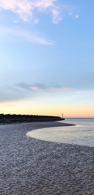 Widok na plażę w Liverpoolu o zachodzie słońca, rzędy falochronów, Wielka Brytania