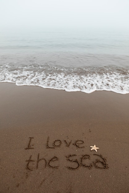 Widok piasku na plaży w lecie z napisaną w nim wiadomością