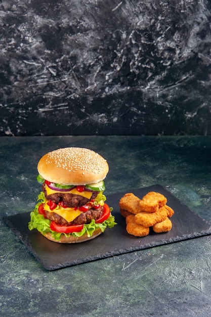 Bezpłatne zdjęcie widok pionowy smaczne kanapki z mięsem z zielonymi pomidorami na tacy ciemnego koloru i bryłkami kurczaka na czarnej powierzchni