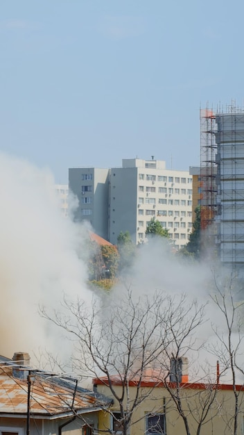 Bezpłatne zdjęcie widok płomieni wychodzących z płonącego domu w krajobrazie miasta. opary i smog wydobywające się z budynku w ogniu, podczas gdy strażacy próbują ugasić niebezpieczny dym wodą.