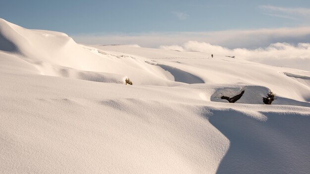 Widok pokrytego śniegiem szczytu góry z samotnym turystą i pochmurny horyzont
