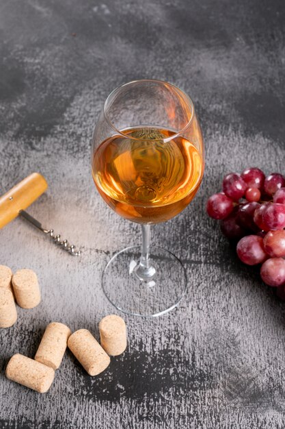 Widok z boku białego wina z winogron na czarnym kamieniu pionowym