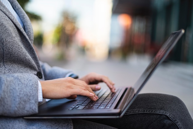 Widok z boku bizneswoman pracuje na laptopie na zewnątrz