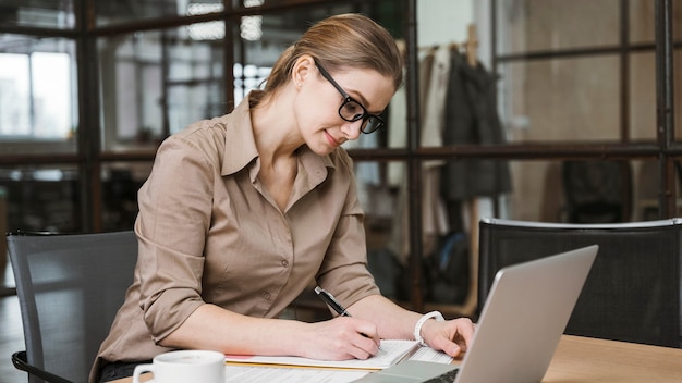 Widok z boku bizneswoman pracy z laptopem przy biurku