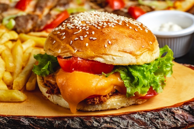 Widok z boku burger z kurczaka z głębokim ogniem z serem pomidorowym i sałatą między bułkami burgerowymi